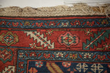 Antique Heriz runner's original macrame fringe and rich red border with traditional floral motifs.