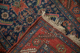Folded corner of antique Heriz rug shows Herati design, hand-knotted foundation, and macrame fringe.