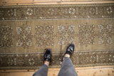 Distressed Melas runner showing repeating quatrefoil medallions and geometric borders in dusty ochre.