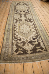 Angled view of a distressed Hamadan runner highlighting the length and repeating geometric medallions.