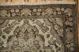 Corner of a vintage Persian Dargezine runner with a chocolate brown floral border and ivory fringe.