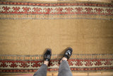 Antique Caucasian runner, camel open field, madder red reciprocating pawn borders, shown with feet.