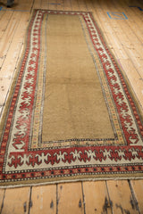 Antique Caucasian runner showing the madder red and ivory reciprocating pawn border on a camel field.