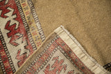 Antique Caucasian runner with restored side selvage, red geometric border, and natural camel hair field.