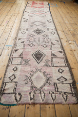 Angled perspective down the length of a distressed Moroccan runner with asymmetric diamond medallions.