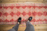 Thick shaggy pile of the distressed Moroccan runner, red and ivory geometric pattern underfoot.