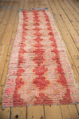 Distressed vintage Moroccan runner with shaggy pile and faded red diamond pattern.