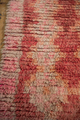 Thick shaggy wool pile showing faded cherry, raspberry, and ivory hues.