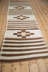 Moroccan runner with ivory and coffee brown horizontal stripes and checkered geometric motifs.