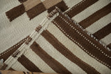 Moroccan rug runner detail: dark copper stripes, ivory dashed patterns, and woven selvage.
