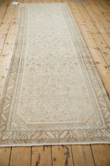 Secured end of distressed Hamadan runner, showing worn pile and beige serrated leaf border.