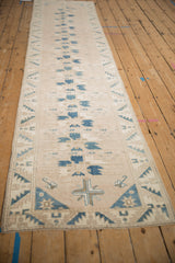 A long distressed Oushak runner seen from an angle, displaying its repeating blue geometric motifs.
