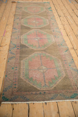 Distressed vintage runner detail: blush and jade geometric medallions with abrashes and pile wear.