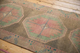 Serrated geometric medallion and leaf border with blush, jade green, and distressed pile.