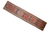 Antique Persian Malayer runner with a column of tomato red medallions on a dark navy field of blossoms.