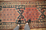 A person's view of the stepped medallions and floral bouquets on an antique Malayer runner.
