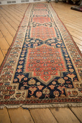 Angled perspective of an antique Malayer runner's repeating red and navy central medallions.