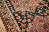 Stepped medallion corner of an antique Malayer rug with floral motifs on a dark navy field.