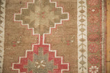 Stepped geometric pattern in blush, olive, and sand with heavy abrashes on this vintage Kurd rug.