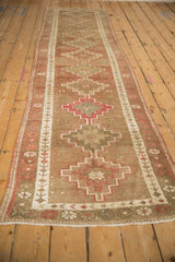 Distressed Kurd runner featuring dusty red and sand geometric medallions and vine border.