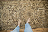 Looking down at the worn texture and geometric patterns of a vintage Karaja runner.