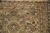 Geometric serrated leaves and floral details on a distressed Karaja rug corner in earthy tones.