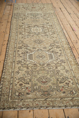 Angled view of a vintage Karaja runner showing its repeating geometric medallions and distressed, sand-colored field.
