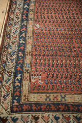 Antique Kurdish Hamadan runner's traditional geometric border, visible side selvage, and madder red boteh field.