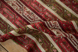 A folded vintage Anatolian runner showing the textured pile of its red, green, and ivory design.