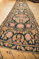 A low angle perspective of the antique Karabagh runner's intricate floral bouquets on a navy field.