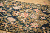 Angled close-up of intricate floral bouquets and the time-softened texture of an antique Karabagh runner.