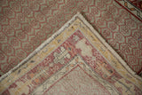 Vintage Oushak rug folded, revealing hand-knotted back and cherry red geometric floral design.