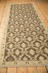 Distressed Oushak runner's coffee brown Rococo floral pattern and side selvage.