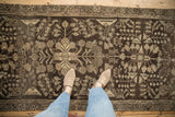 Distressed chocolate brown Dargezine runner with faded floral bouquets under feet.