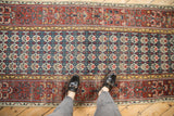Antique Bijar runner's quatrefoil floral field in ivory, navy, cherry, and henna design border.