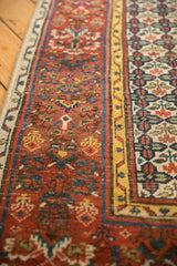 Antique Bijar runner's cherry red field and saffron yellow henna plant border.