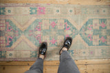 Distressed vintage Oushak runner with muted cream, magenta, and teal geometric patterns underfoot.