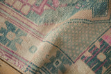 Textured pile of vintage distressed Oushak runner in muted teal and pink geometric motifs.
