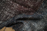 Distressed Sparta rug with mostly even wear showing textured violet, teal, charcoal pile.