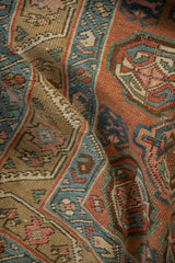 Antique runner's textured pile and geometric guls in muted blue, red, and olive tones.