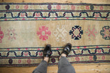 Distressed Kurd rug runner displays pink and navy geometric motifs on a golden field with abrashes.