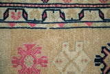 Distressed Kurd rug with textured gold field, navy geometric border, and bubblegum pink motifs.
