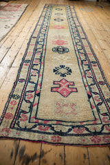 Distressed vintage Kurd runner with gold abrash field, navy, and pink geometric patterns.