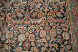 Antique Persian Khorassan detail: worn madder red vinery and dusty gold on deep navy ground.