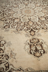 Decorative arabesque details and even low pile of a distressed Tabriz carpet in sand and brown.