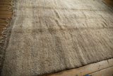 Textured pile and fringe of a vintage Moroccan carpet in natural beige and sand tones.