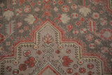 Distressed Vintage Khotan carpet detail: brick red floral motifs on a time-softened silver spandrel.