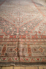 Distressed Khotan carpet with brick red floral pinwheel motifs on a time-softened neutral ground.