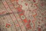 Textured vintage surface of Khotan carpet, revealing brick red floral pinwheels and softened tones.
