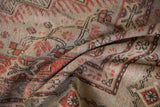Distressed vintage Khotan carpet showing faded floral patterns and visible knot heads.